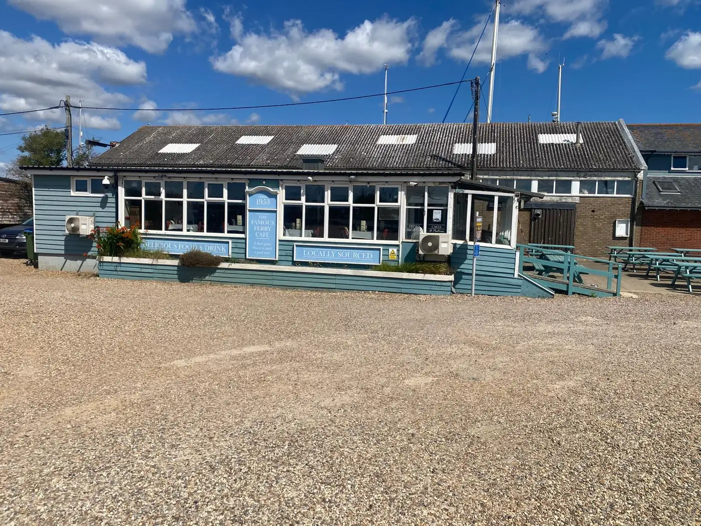The Famous Ferry Cafe at Felixstowe Ferry, the blue clapboard building with outdoor seating on a sunny day